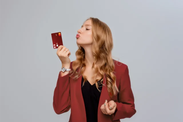 Woman holding Monroe debit card making a kissing face.